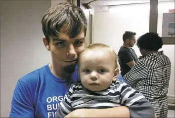  ?? Don Hopey/Post-Gazette ?? East Liverpool resident Gregory Kiger and his 13-month-old son, Jeremiah, attend a meeting last week where manganese study results were released. “My pediatrici­an recommende­d my children have their blood tested, and I’ll be getting that done,” said...