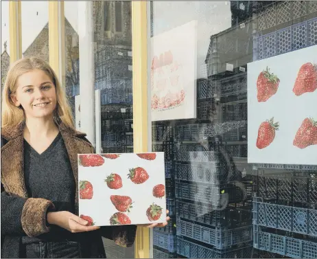  ??  ?? POP-UP DISPLAY Artist Dominique Warren at the shop window in Southsea with her painting of strawberri­es