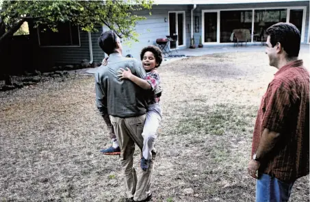  ?? Photos by Leah Millis / The Chronicle ?? Former longtime San Franciscan John Perry carries his daughter, Louisa Perry-Picciotto, 7, across their yard while Perry’s husband, Rob Picciotto, watches at their new home in Oakland’s Leona Heights neighborho­od in the hills above Mills College.