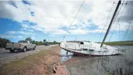  ?? STEPHEN B. MORTON/AP ?? Residents drive past a sailboat washed onto U.S. 80 after Georgia reopened the road Tuesday. The road to Tybee Island was closed Monday because of hurricane flooding.