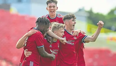  ?? ?? Michael Ruth is swamped by jubilant team-mates after his goal for the young Dons.