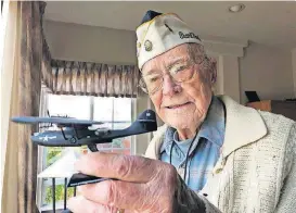  ?? [AP PHOTO] ?? Retired U.S. Navy Cmdr. Don Long, at his home Friday in Napa, Calif., holds up a replica of the military seaplane he was standing watch on when Japanese warplanes attacked Hawaii 77 years ago.
