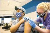  ?? STEPHEN M KATZ/STAFF ?? EVMS medical student Emery Cuellar gives public health student Sydney Harper the Pfizer COVID-19 vaccine at EVMS on Friday.