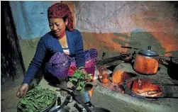 ??  ?? Sun Kumari Gurung cooking in her home in Uhiya village