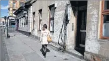  ??  ?? A woman walks past exposed wires at a property on Argyle Street which backs on to Ardgowan Terrace Lane