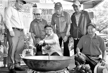  ??  ?? Ishak Ismail (centre) stirring the Gula Apong as a launching gimmick at Medan Niaga Satok yesterday. - Bernama photo