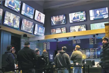  ?? Steven Senne / Associated Press ?? Patrons visit the sports betting area of Twin River Casino in Lincoln, R.I., in this Nov. 18, 2019, photo. Gambling regulators and sports books in several U.S. states were preparing to allow gamblers to bet on XFL games when the league’s season began this past Saturday.