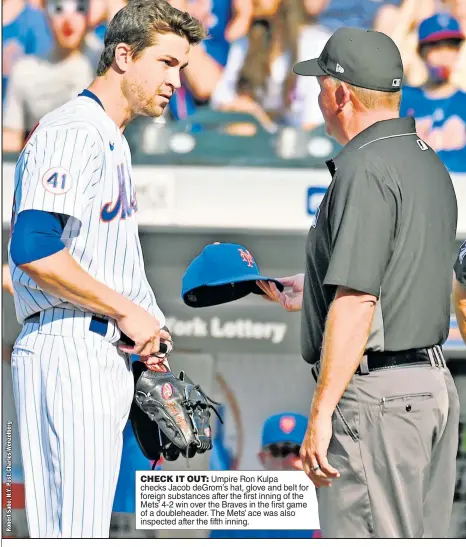  ??  ?? CHECK IT OUT: Umpire Ron Kulpa checks Jacob deGrom’s hat, glove and belt for foreign substances after the first inning of the Mets’ 4-2 win over the Braves in the first game of a doublehead­er. The Mets’ ace was also inspected after the fifth inning.