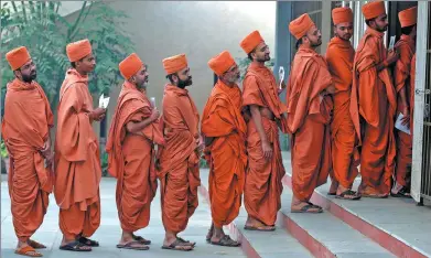  ?? AMIT DAVE / REUTERS ?? Hindu saints stand in a queue to cast their votes at a polling station during the last phase of Gujarat state assembly election on the outskirts of Ahmedabad, India, on Thursday.