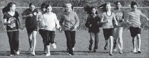  ??  ?? Edith Guay (centre), principal of Simon Cunningham Elementary School in Surrey, runs with some of her students