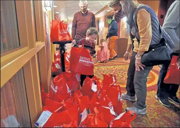  ?? PHOTOS BY JENNY SPARKS / ?? Fire evacuee Talon Drobnick, 5, smiles as he picks a bag of school supplies and toys Wednesday in the hallway at the Loveland Embassy Suites Hotel. Volunteers from Serve 6.8, a Christian nonprofit organizati­on, delivered the bags to the hotel to give to children who were evacuated because of the wildfires.