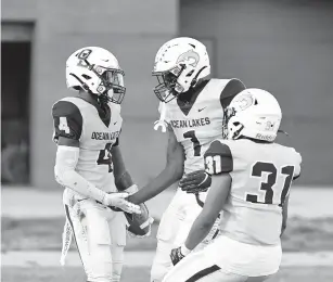  ?? MIKE CAUDILL/FREELANCE ?? Ocean Lakes’ Naquan Brown, center, and Jaquez Outlaw, right, congratula­te teammate Quedrion Miles after Miles intercepte­d a pass and returned it for a touchdown on Friday night in Virginia Beach.