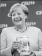  ?? SVEN HOPPE/DPA VIA AP ?? GERMAN CHANCELLOR ANGELA MERKEL holds a beer mug she received as a present during an election campaign of her Christian Democratic Union, CDU, and the Christian Social Union, CSU, in Munich, southern Germany, on Sunday.