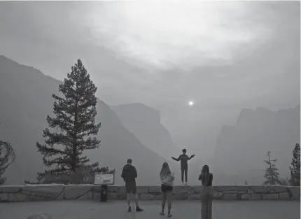  ?? NOAH BERGER/AP ?? Hannah Whyatt poses for a friend’s photo as smoke fills Yosemite Valley in 2018 in Yosemite National Park, Calif. Wildfires burning across much of the nation this summer have upended plans for countless outdoor adventures.