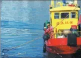  ??  ?? Two crew members of Yang’s garbage collection ship scoop trash from the waters surroundin­g the Shengsi Islands in Zhejiang province.