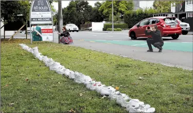  ?? AP/MARK BAKER ?? People photograph a memorial Monday of 50 pairs of white shoes for the victims of Friday’s mosque shootings in front of a church in Christchur­ch, New Zealand.