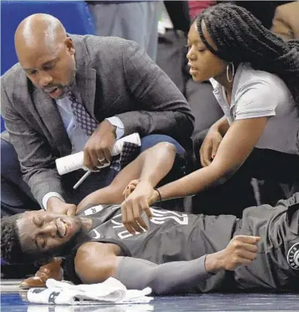  ?? AP ?? Trainers tend to Caris LeVert after Net guard hurts leg in second quarter of loss to Timberwolv­es in Minnesota.