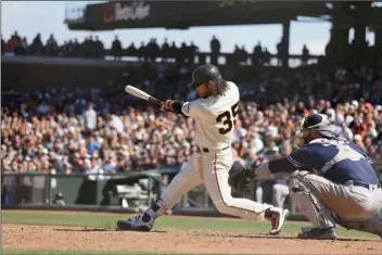 ??  ?? San Francisco Giants’ Brandon Crawford hits a game-winning single off San Diego Padres relief pitcher Brad Hand in the 10th inning of a baseball game Wednesday in San Francisco. San Francisco won the game 4-3. Looking on at right is Padres catcher...