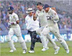  ?? — AP ?? Players and umpire run off the pitch after a sudden downpour on Friday.