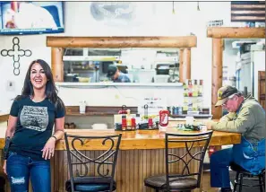 ??  ?? Feeling protected: Gun-toting Boebert (left) standing by the counter with a customer inside Shooters Grill in Rifle, Colorado. — AFP