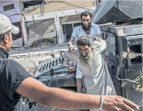  ??  ?? Iraqi Special Operation Forces soldiers bring two captured Isil militants to a screening centre in Mosul’s Old City, where a few hundred diehards still hold civilians as human shields