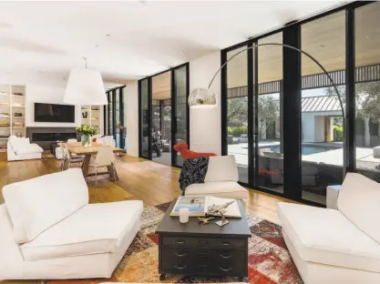  ?? Photos by John Wilson / Circle Visions ?? Above: The living room at 1318 Stockton St. in St. Helena looks out to a sunny courtyard through floor-to-ceiling windows. Below left: The exterior landscape includes a gas fire pit. Below right: Floor-to-ceiling built-ins and surround sound speakers...