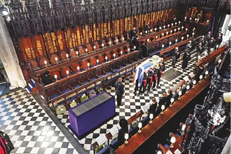  ?? Reuters ?? Queen Elizabeth II (corner left) watches as pallbearer­s carry the coffin of Prince Philip at St George’s Chapel in Windsor yesterday.