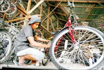  ?? HENG CHIVOAN ?? A man repairs a bicycle at a market in the capital’s Tuol Kork district in 2021.