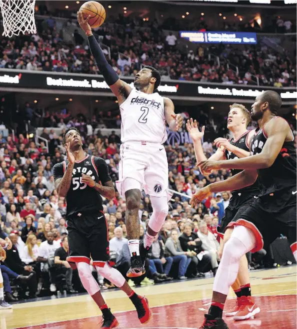  ?? NICK WASS/THE ASSOCIATED PRESS ?? Washington Wizards guard John Wall goes to the basket surrounded by Toronto Raptors Delon Wright, left, Serge Ibaka, right, and centre Jakob Poeltl during the second half of Game 4, a half in which the Wizards made a double-digit comeback to win 106-98...