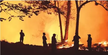  ?? — AFP photo ?? Residents look at a forest fire in El Hatillo, Francisco Morazan department, Honduras. Hundreds of hectares were destroyed by the flames in El Hatillo, near La Tigra national park.