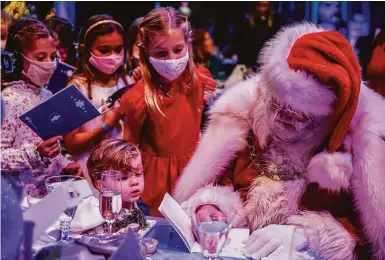  ?? Photos by Brontë Wittpenn / The Chronicle ?? Santa Claus (Douglas McKechnie) signs autographs for kids during a luncheon before the “Nutcracker.”