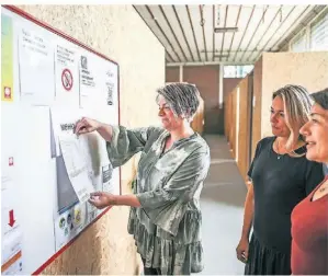  ?? FOTO: LARS FRÖHLICH ?? Stefanie Vahnenbruc­k, Violetta Glabian und Monika Liesenfeld von der Caritas stehen vor der Tafel, die den Geflüchtet­en Infos gibt.