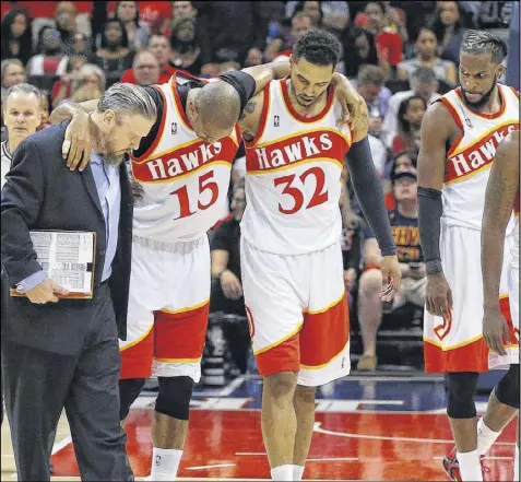  ?? CURTIS COMPTON / CCOMPTON@AJC.COM ?? Al Horford (center) is helped off the court by Mike Scott and a Hawks trainer after an apparent knee injury. Horford returned briefly before going to the bench for the remainder of the game.