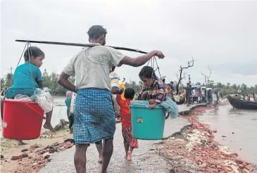  ??  ?? BURDEN OF LOVE: A Rohingya refugee carries two children as they arrive in Bangladesh at Shah Porir Dwip in Teknaf.