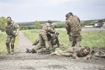  ?? AFP ?? Ukrainian servicemen assist their comrades not far from the frontline in Donbas on Saturday amid the Russian invasion of Ukraine.