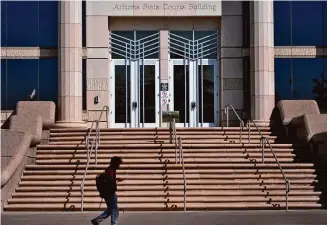  ?? Matt York/Associated Press ?? A person walks past the Arizona Supreme Court building on April 10 in Phoenix. The near-total abortion ban resurrecte­d last week by the Arizona Supreme Court dates to 1864, a time when gold-seekers were moving in, dueling had to be regulated and the U.S. Army was forcibly removing Native Americans from their land.