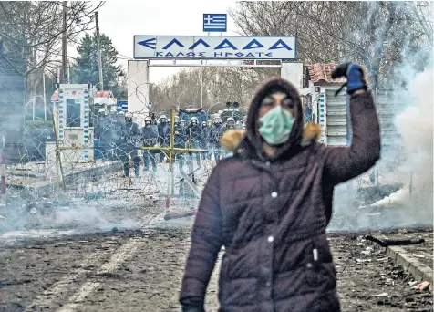  ??  ?? A migrant walks away from the border as Greek police fire tear gas. Below, a woman and children sit in a dinghy during an attempt to enter Greece by crossing the Maritsa river