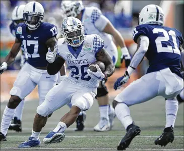  ?? JOE ROBBINS / GETTY IMAGES ?? Kentucky’s Benny Snell Jr., who rushed for 144 yards and two touchdowns, looks to evade Penn State cornerback Amani Oruwariye during the first quarter of the Citrus Bowl in Orlando, Fla., on Tuesday.