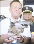  ?? RUDY SANTOS ?? Customs Commission­er Isidro Lapeña holds a soft-shell turtle, one of 123 seized last Friday, during a press conference at the NAIA yesterday.