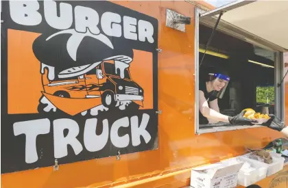  ?? DAVE SIDAWAY ?? Burger Truck employee Jamii Kingston serves a customer in St-lambert on Tuesday. Food trucks will be coming to the downtown Ville-marie borough beginning Monday and to the Rosemont—la-petite-patrie and Hochelaga-maisonneuv­e boroughs in early July.