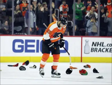  ?? TOM MIHALEK — THE ASSOCIATED PRESS ?? Philadelph­ia Flyers’ captain Claude Giroux skates past hats thrown by the fans after he scored his third goal of the game Saturday against the New York Rangers. The Flyers clinched a playoff berth with a 5-0 win in the regular season finale.