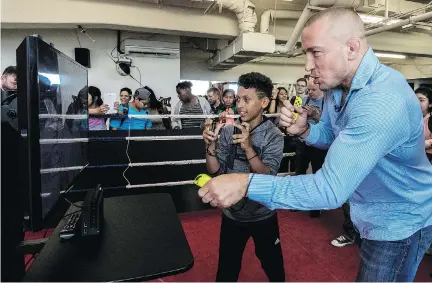  ?? DAVE SIDAWAY ?? MMA fighter Georges St-Pierre competes against 12-year-old Shakir Djermane at Nintendo’s ARMS video game setup at Centre Père Sablon on Friday. St-Pierre was on hand to reward Shakir and other students for their work on an anti-bullying campaign for...