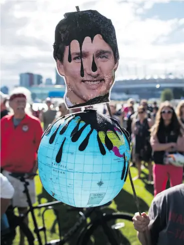  ?? DARRYL DYCK / THE CANADIAN PRESS ?? A protester holds a photo of Prime Minister Justin Trudeau in Vancouver on Tuesday during a protest against the Kinder Morgan Trans Mountain Pipeline expansion.