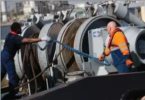  ?? (AP/Virginia Mayo) ?? Ship engineer Wim Giabeler (right) and deckhand Gerard Bakulikira (left) wear Romware COVID Radius digital bracelets as they work on deck of a tugboat in the Port of Antwerp, Belgium. The Port of Antwerp and technology company Rombit are testing a digital bracelet aimed at preventing the spread of the coronaviru­s.