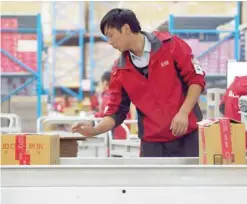  ?? — AFP ?? A Jd.com employee checks goods from a conveyor belt at a warehouse in Langfang, China’s Heibei province.