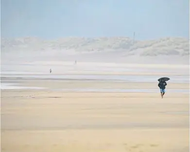  ?? Eloy Alonso / EFE ?? Las Salinas. La playa, en el término municipal de Avilés, en una imagen tomada ayer cuando, entre la bruma y una ligera lluvia, algunas personas paseaban por la arena