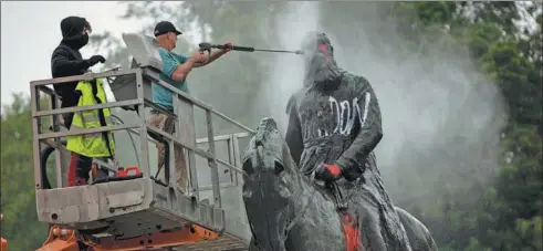  ?? FRANCISCO SECO / AP ?? Workers clean graffiti from a statue of King Leopold II in Brussels, the Belgian capital. The statue was targeted by protesters during a demonstrat­ion in June.