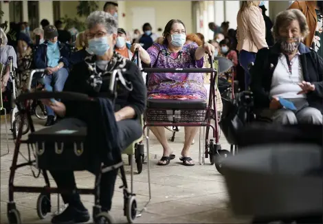  ?? THE ASSOCIATED PRESS THE ASSOCIATED PRESS ?? Resident Sabeth Ramirez, 80, center, waits in line with others for the Pfizer-BioNTech COVID-19vaccine at the The Palace assisted living facility in Coral Gables, Fla.