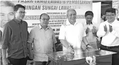  ??  ?? Awang Tengah signing the plaque to commemorat­e the start of the Lawas Tamu project as others look on.