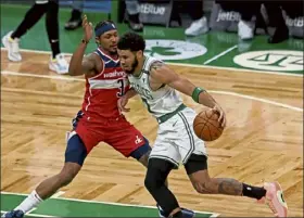  ?? STUART cahill / BOSTON Herald File ?? Jayson Tatum, driving to the basket against Washington’s Bradley Beal on Friday night, has tested positive for covid-19 twice. Beal was pulled from the Wizards’ lineup shortly before Saturday’s game against the Miami Heat.